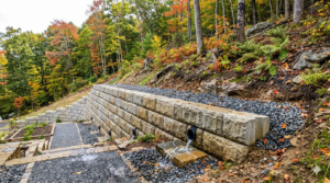 Engineered concrete block retaining wall with weep holes securing a steep mountain slope residential property in Boone NC