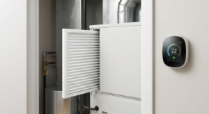 Close-up of a high-efficiency residential HVAC unit showing a standard 1-inch air filter being removed next to a smart thermostat.